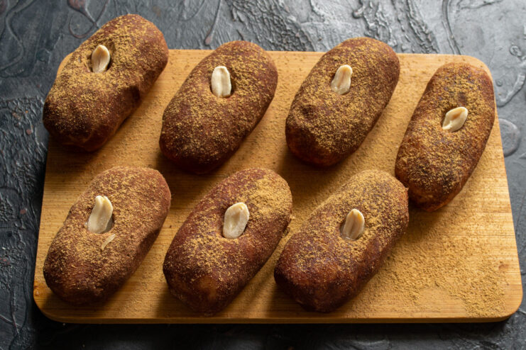 Decorating the cakes to look like potatoes with sprouts A close-up of a finished Pirozhnoe Kartoshka decorated with a honey-dipped peanut to resemble a sprouted eye.