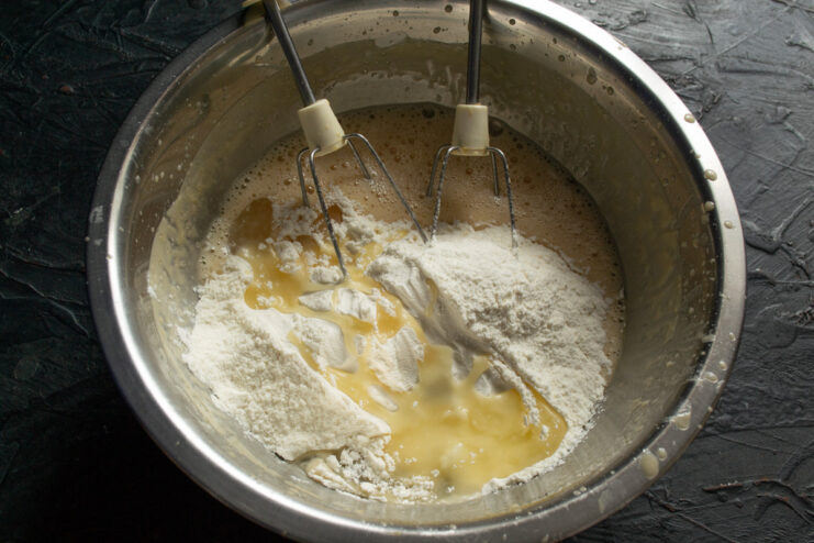 Adding all-purpose flour to the cake batter Adding all-purpose wheat flour to the wet ingredients in a mixing bowl.