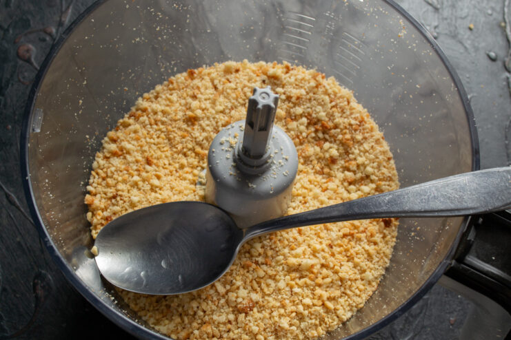 Mixing cake crumbs, peanuts, and whiskey A bowl with sponge cake crumbs and ground peanuts, with whiskey being poured in.