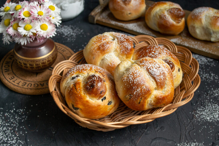 A plate of freshly baked Plyushki with raisins, dusted with powdered sugar.