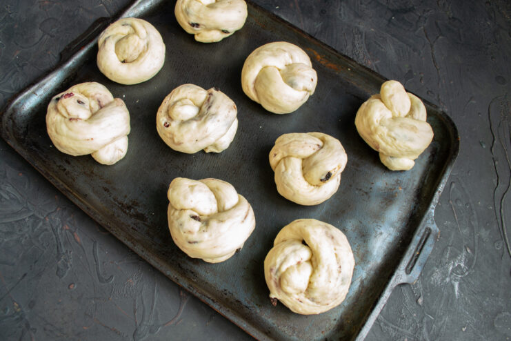 Step 11: Arranging the shaped plyushki on a baking sheet for proofing. Several shaped, unbaked plyushki arranged on a parchment-lined baking sheet, ready to rise.