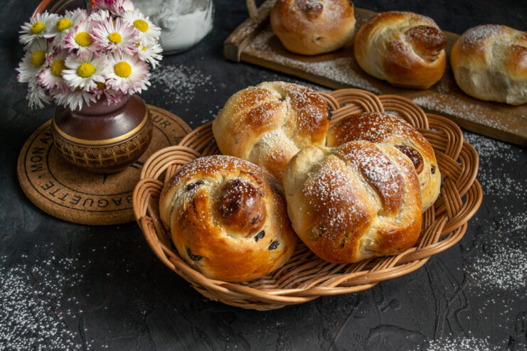 Enjoying freshly baked Plyushki with a dusting of powdered sugar. A beautiful arrangement of warm, golden plyushki with raisins, generously dusted with powdered sugar.