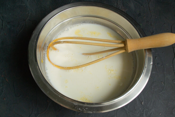 Step 2: Whisking milk with sugar and eggs to create the wet base. Whisking a mixture of milk, sugar, and eggs in a white bowl to form a smooth liquid base.