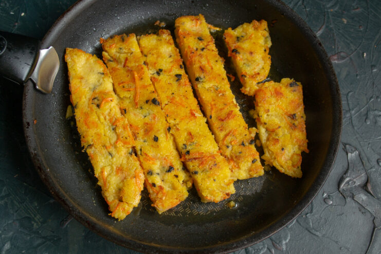 Pan-Frying Polenta Slices until Golden Brown Slices of polenta being pan-fried in a skillet until golden and crispy.