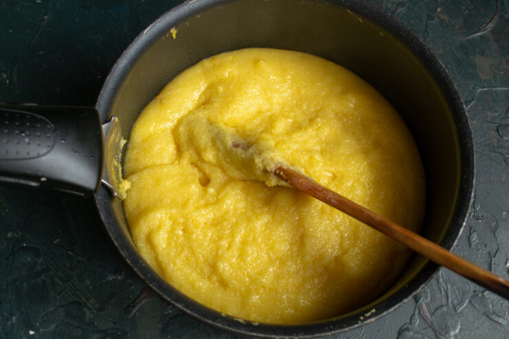 Cooking Polenta until Thick and Creamy Cooking polenta in a pot, stirring with a wooden spoon as it thickens.