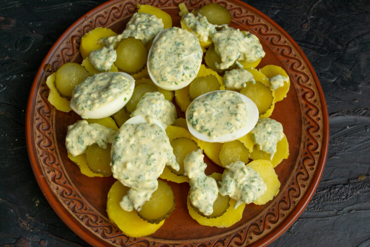 Creating deviled eggs as a garnish for the salad. Halved hard-boiled eggs being filled with the creamy mayonnaise and yolk dressing.