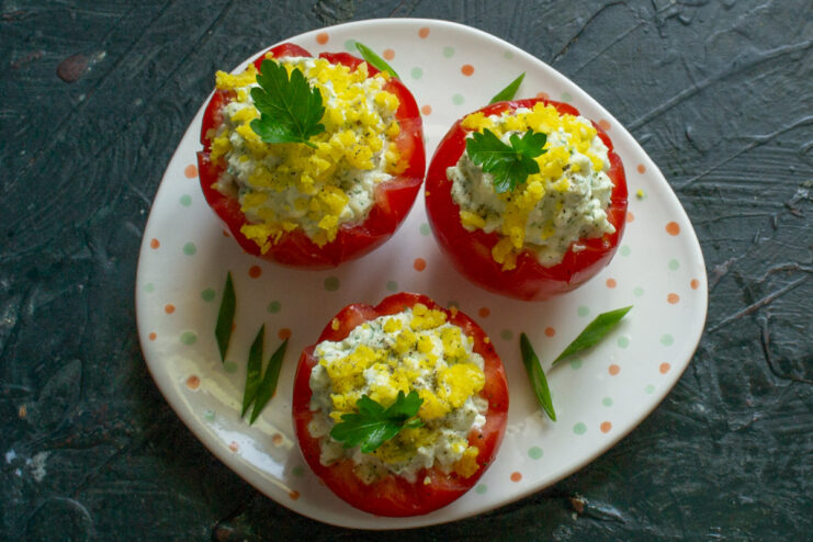 Finished stuffed tomatoes garnished with fresh parsley and chopped green onions, ready to serve.