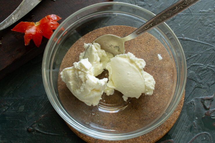 A bowl of creamy white cottage cheese, ready to be mixed into the filling for stuffed tomatoes.