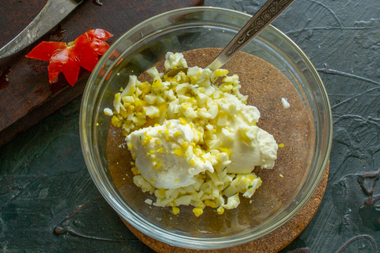 Chopped hard-boiled egg being added to a bowl of cottage cheese to create the stuffing.