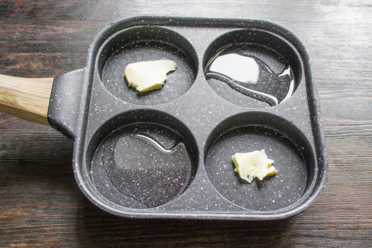 Melting Butter in a Sectioned Pan for Breakfast Small pieces of butter melting in the four compartments of a sectioned frying pan.
