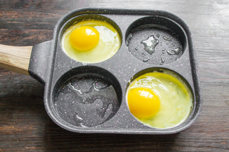Frying Eggs in a Compartment Pan Two eggs being fried sunny-side-up in two sections of a compartment pan.