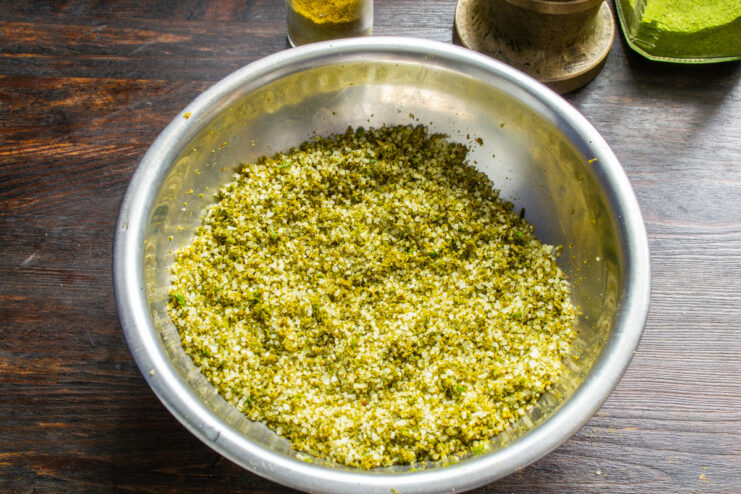 Hand-Mixing the Spiced Salt to Ensure an Even Blend A person wearing gloves is hand-mixing the green spiced salt in a large bowl.