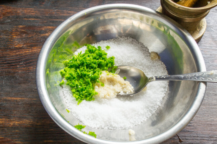 Adding Ground Garlic Scapes to the Salt Mixture Ground green garlic scapes being added to a bowl of coarse sea salt.