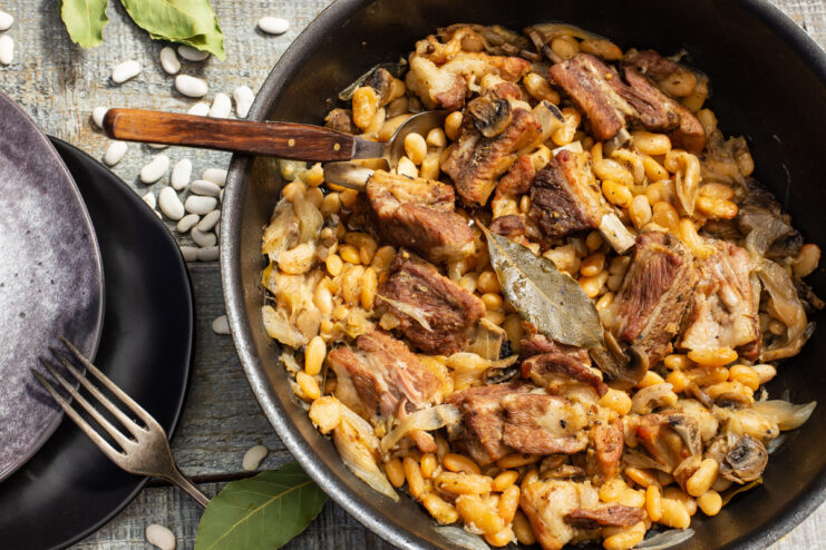 A bowl of hearty white bean and ribs stew, garnished with fresh herbs.