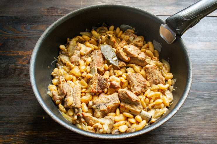 Simmering the stew slowly allows the flavors to meld and the meat to become tender. A covered skillet of stew simmering on a stovetop, with steam escaping.