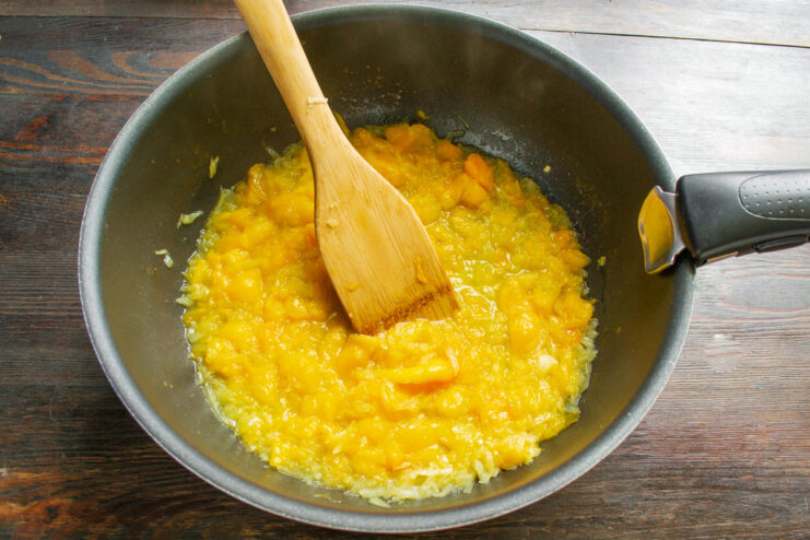 Simmering the Pumpkin Until Tender Pumpkin and onion simmering in a skillet to make the base for the stew.
