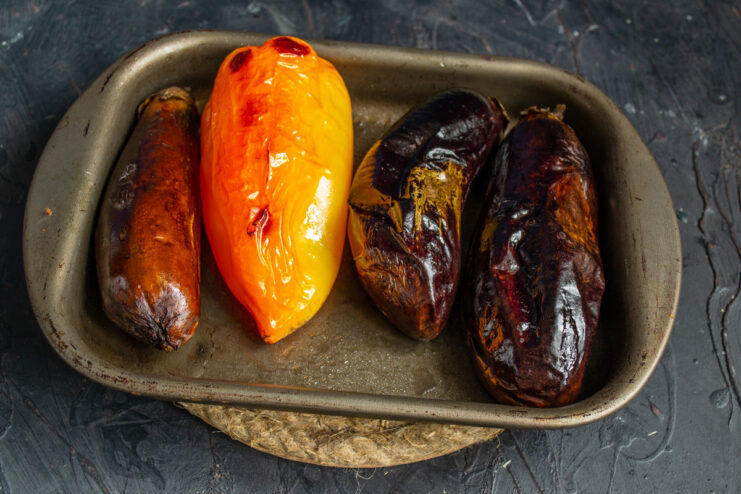 Roasting Vegetables in the Oven to Develop a Deep, Smoky Flavor A baking sheet with eggplants and bell peppers roasting inside an oven.