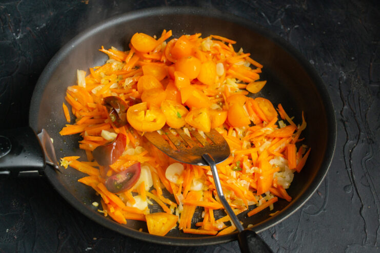 Adding Fresh Yellow Tomatoes to the Vegetable Base Chopped yellow tomatoes being added to the skillet with other vegetables.