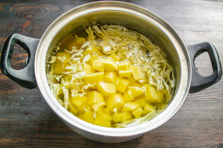 Preparing Potatoes for a Hearty Soup Peeled potatoes being diced into large cubes on a wooden cutting board.