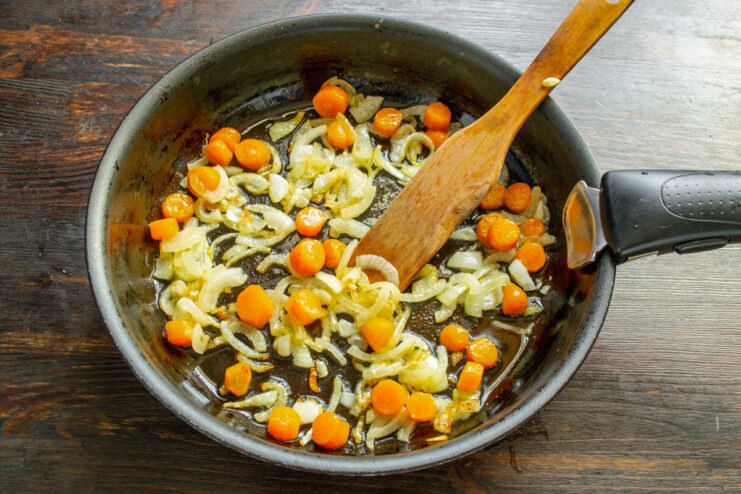 Creating the Flavor Base: Sautéing Onions and Carrots Sliced onions and carrots being sautéed in a skillet until softened.