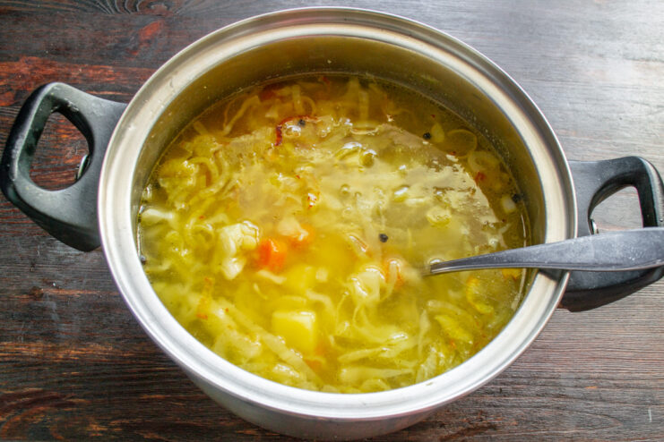 Simmering the Vegetables to Tenderness A pot of soup with cabbage and potatoes simmering on the stove.