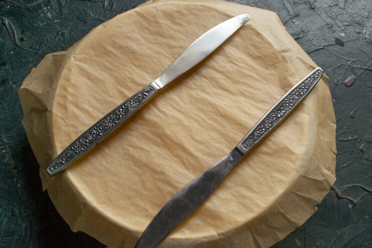 Covering the dish with parchment paper to steam the rice perfectly. A baking dish with plov ingredients being covered with a sheet of parchment paper.