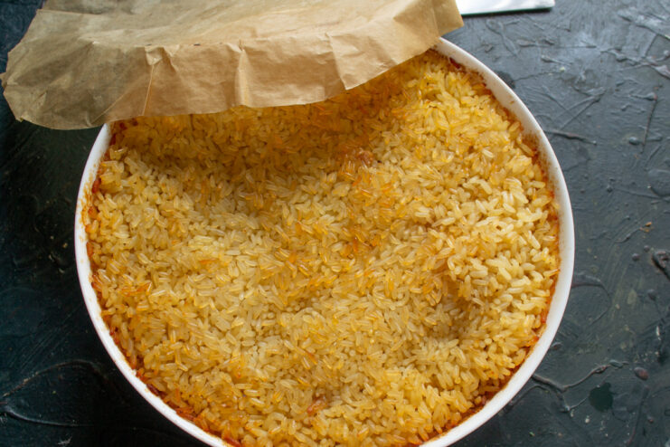 Baking the plov: starting high and then reducing the temperature. The baking dish with plov being placed into a hot oven.