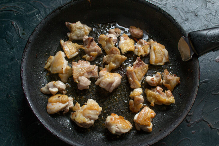 Pro tip: Frying chicken in batches ensures a perfect golden-brown crust. Chicken pieces being fried in batches in a hot skillet to achieve a golden-brown color.