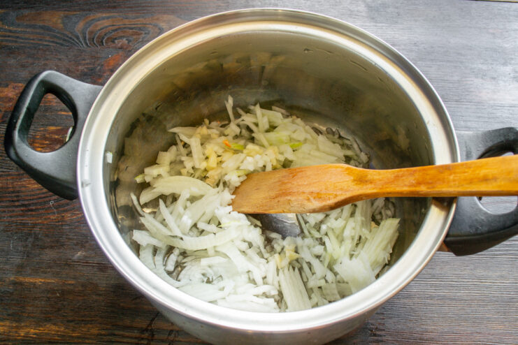 Dicing an onion on a cutting board for the ratatouille base. Close-up of a chef's hands finely dicing a yellow onion on a wooden cutting board.