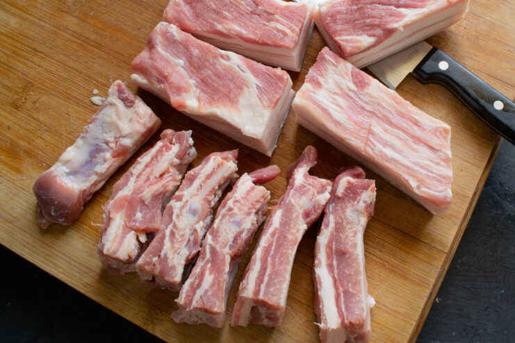 How to Prepare Pork Ribs: Removing the Membrane for Tender Results Hands cutting a rack of pork ribs into individual pieces on a cutting board.