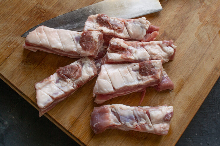Scoring the Ribs - A Simple Step for Better Searing Close-up of pork ribs being scored with a knife to help with cooking.