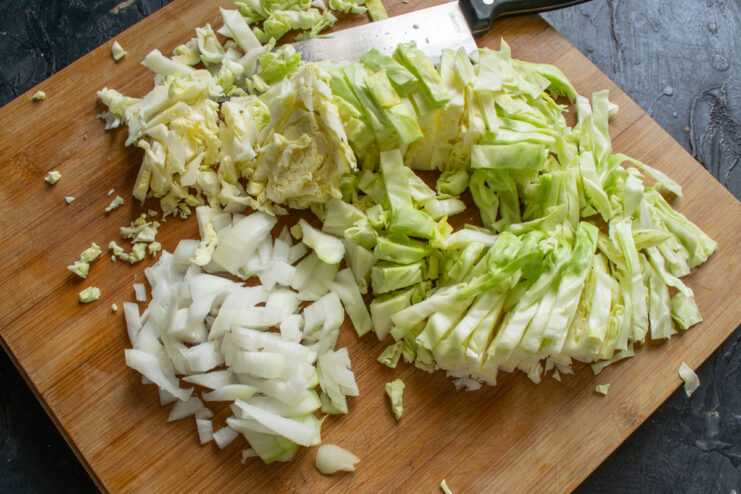 Preparing the Cabbage: How to Shred it for Braising A pile of freshly shredded white cabbage on a cutting board.