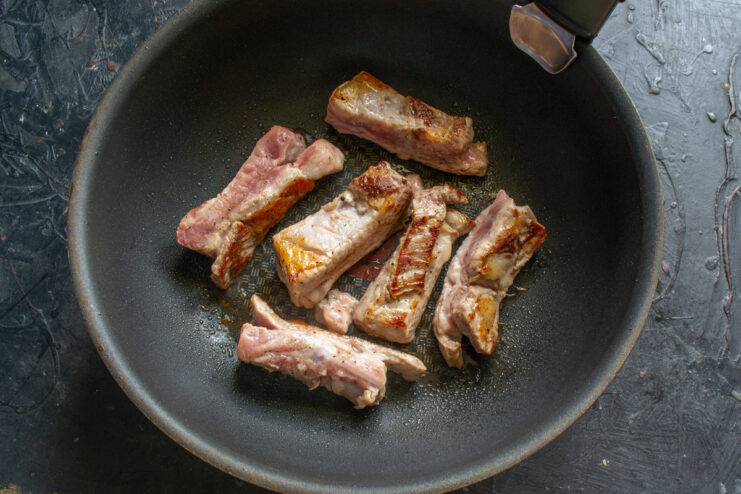 Searing the Ribs to Lock in Flavor and Juices Pork ribs searing in a hot skillet, turning golden brown.