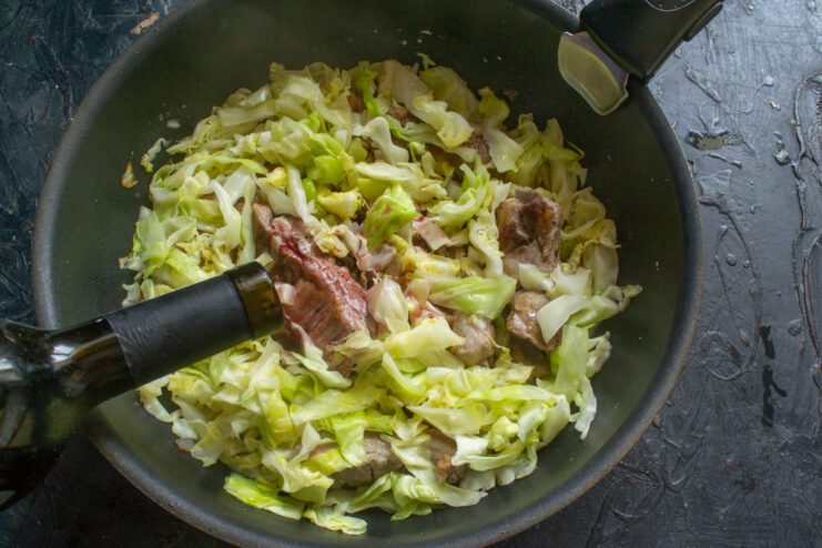 The Secret Ingredient: Deglazing with Red Wine and Thyme Red wine and dried thyme being added to the skillet with ribs and cabbage.