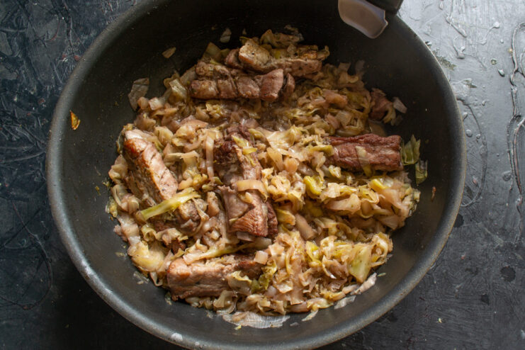 Slow Braising for Tenderness: Let it Simmer A covered skillet simmering on the stove to braise the ribs and cabbage.