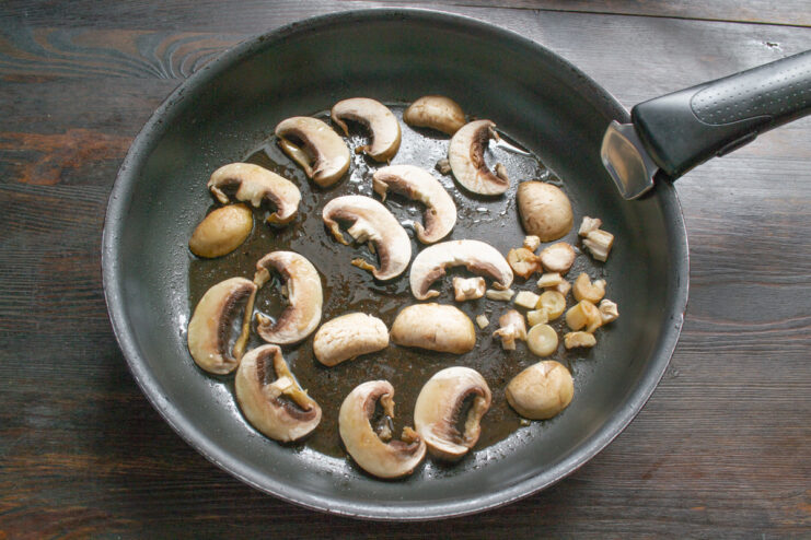 Prepping Mushrooms: Slicing for Even Cooking Fresh champignon mushrooms being sliced thinly on a cutting board.