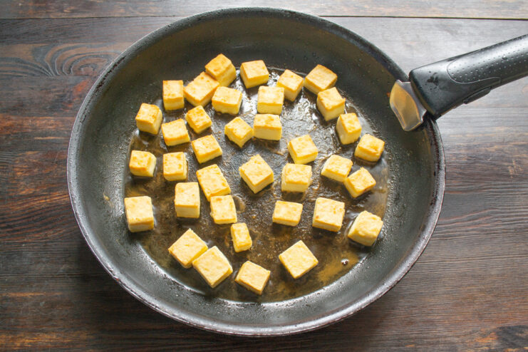 Frying Tofu Cubes Until Perfectly Golden and Crispy Cubed tofu being fried to a golden brown color in a hot pan.