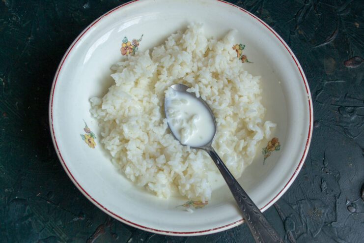 Step 1: Combining cooked rice with milk to create a creamy base for the casserole. A bowl of cooked white rice with milk being poured over it.
