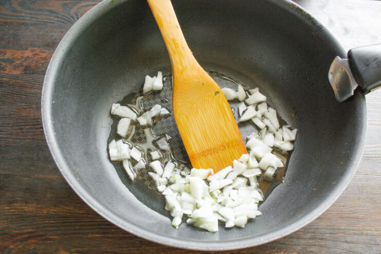 Sautéing Onions to Build the Flavor Base for Risotto Chopped onions being sautéed in a skillet with olive oil until translucent.