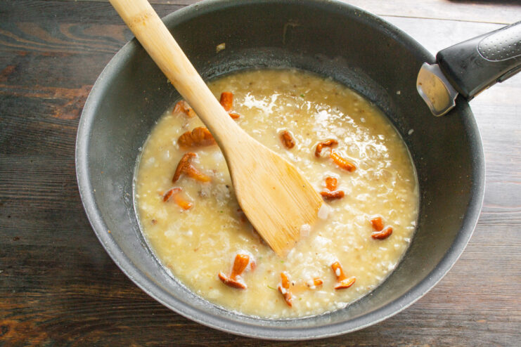 The Gradual Process of Adding Liquid to Risotto Adding a ladle of hot broth to the simmering risotto in a skillet.