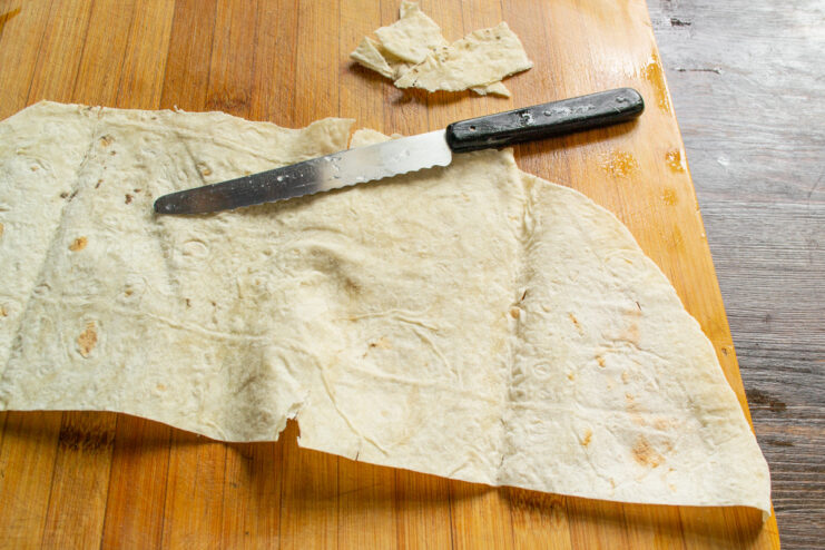 Preparing the lavash base for the cheese roll A rectangular piece of thin lavash bread on a wooden cutting board.