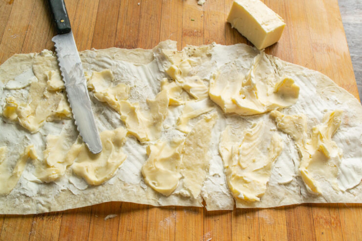 Adding the second layer of cheese to the lavash roll Slices of processed cheese being layered on top of the cream cheese spread on lavash.