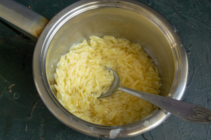 Cooking pasta al dente for the perfect salad base. Small pasta being cooked in a pot of boiling water.