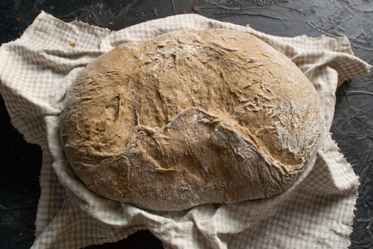 Cold Proofing the Shaped Loaf The shaped rye loaf in a proofing basket, covered with a cloth, ready for cold fermentation in the fridge.