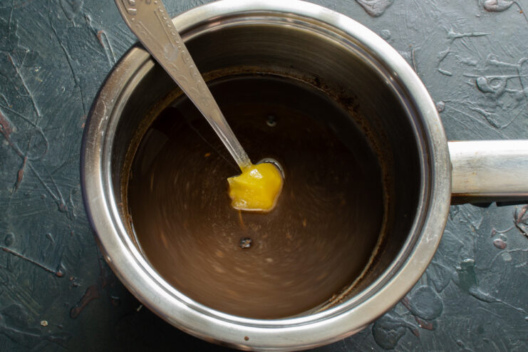 Adding Sweetness and Fat to the Mixture Adding honey and rapeseed oil to the saucepan with other liquid ingredients.