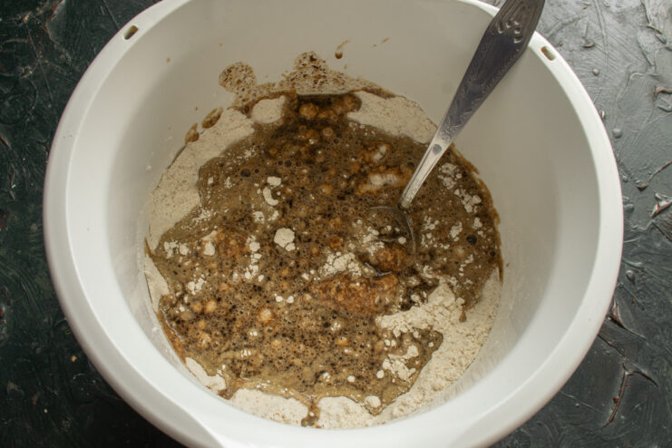 Combining Wet and Dry Ingredients for the Dough Pouring the liquid mixture from a saucepan into a bowl with flour to make the dough.