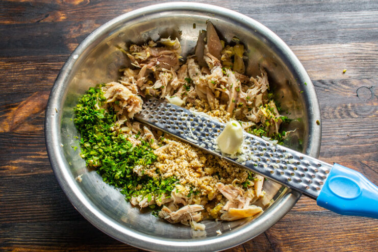 Adding Minced Garlic for a Pungent Kick Minced garlic being added to the bowl of shredded chicken.