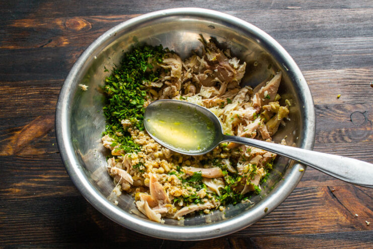 Using Chicken Broth as a Flavorful, Mayo-Free Dressing Strained chicken broth being poured into the bowl with chicken and walnuts.