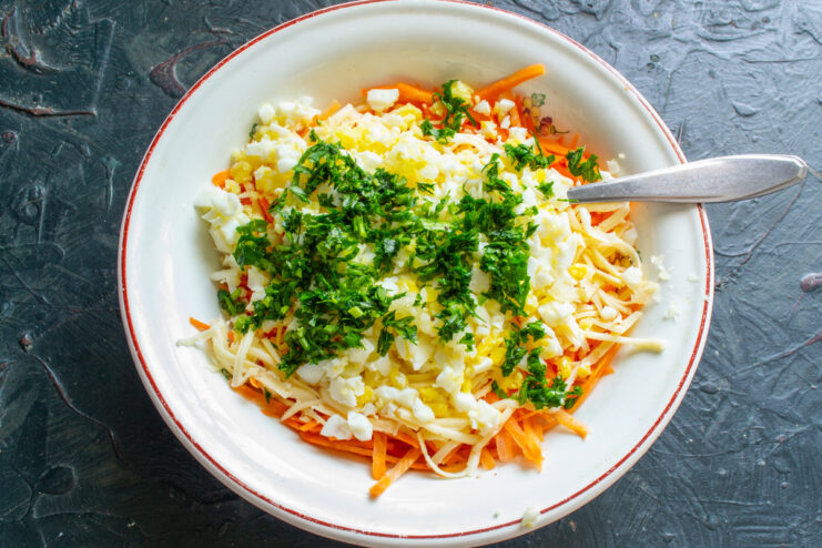 Adding fresh herbs like parsley to brighten the salad's flavor. Chopped fresh parsley being added to the salad bowl.