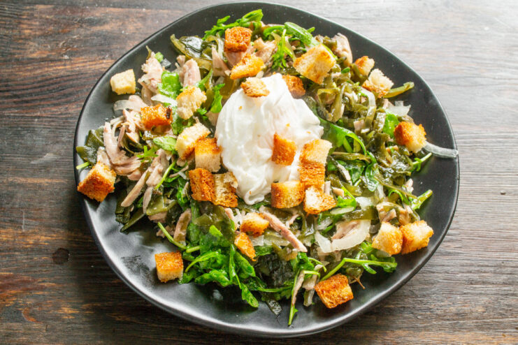 Final Touch: Topping the Salad with Homemade Croutons The finished salad topped with a poached egg and golden-brown croutons, ready to be served.